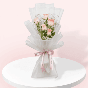 A small bouquet of 5 stem light pink rose, with greenery, wrapped in white, and tied with a baby pink ribbon.