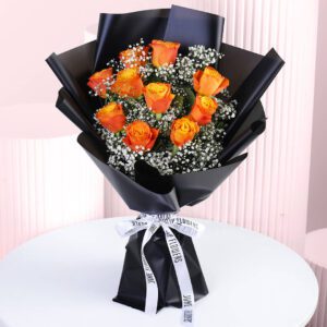 A bouquet of orange rose bouquet wrapped in black paper